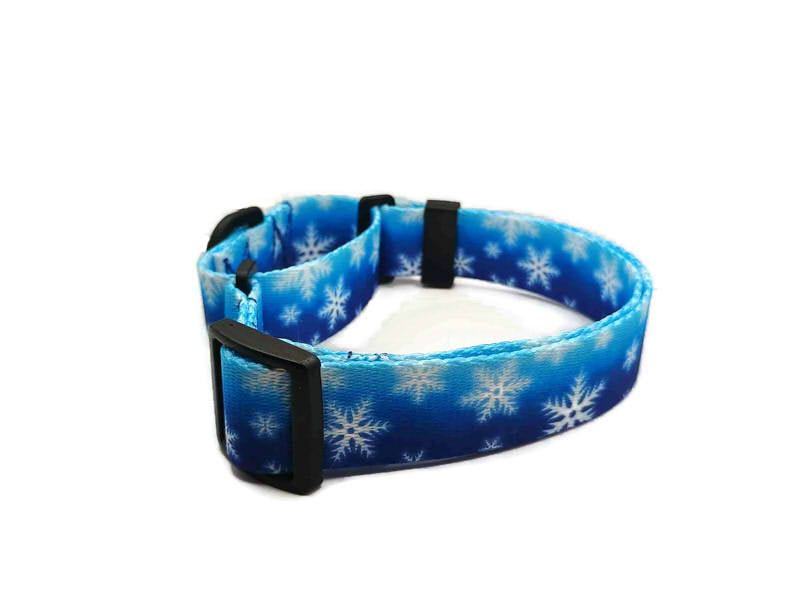 White snowflakes on a cold wintery blue background. This collar features plastic hardware, which is ideal for dogs allergic to metal or service dogs going thru TSA checkpoints.